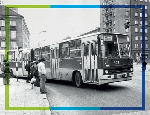 Zdjęcie archiwalne. Autobus marki Ikarus porusza się po ulicach Białegostoku. Przed przejściem dla pieszych stoją ludzie oczekując na zielone światło.